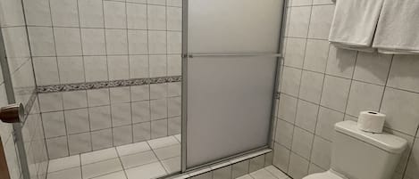 A bathroom with a shower, toilet, and a towel rack.