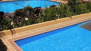 Relax by the pool surrounded by lush greenery and lounge chairs.