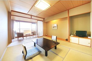 Una habitación de estilo japonés tradicional con suelo de tatami, una mesa baja y un televisor sobre un mueble.