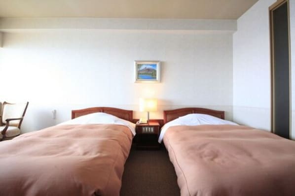 A hotel room with two single beds, a nightstand with a lamp, a chair, and a framed picture on the wall. - Heiseikan Shiosaitei (Hakodate)