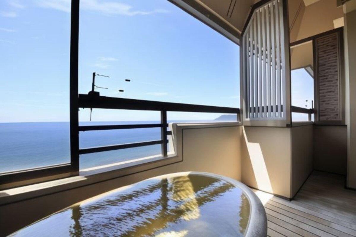 A balcony with a view of the sea, a glass table, and a wooden floor.