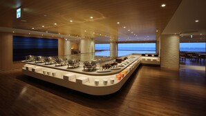 Un hall d’hôtel moderne avec un espace buffet proposant différents stands de restauration et offrant une vue sur l’océan.