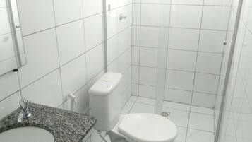 Un bagno con lavabo su piano in granito, water e cabina doccia rivestita di piastrelle bianche.