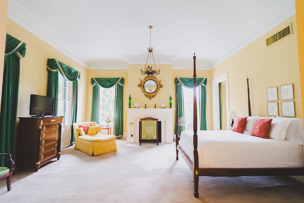 Un dormitorio amplio con una cama grande, televisión, chimenea y cortinas verdes.