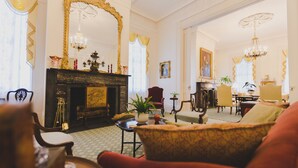 A room with a fireplace, a large mirror, and a red armchair. - Brandon Hall Plantation (Natchez)