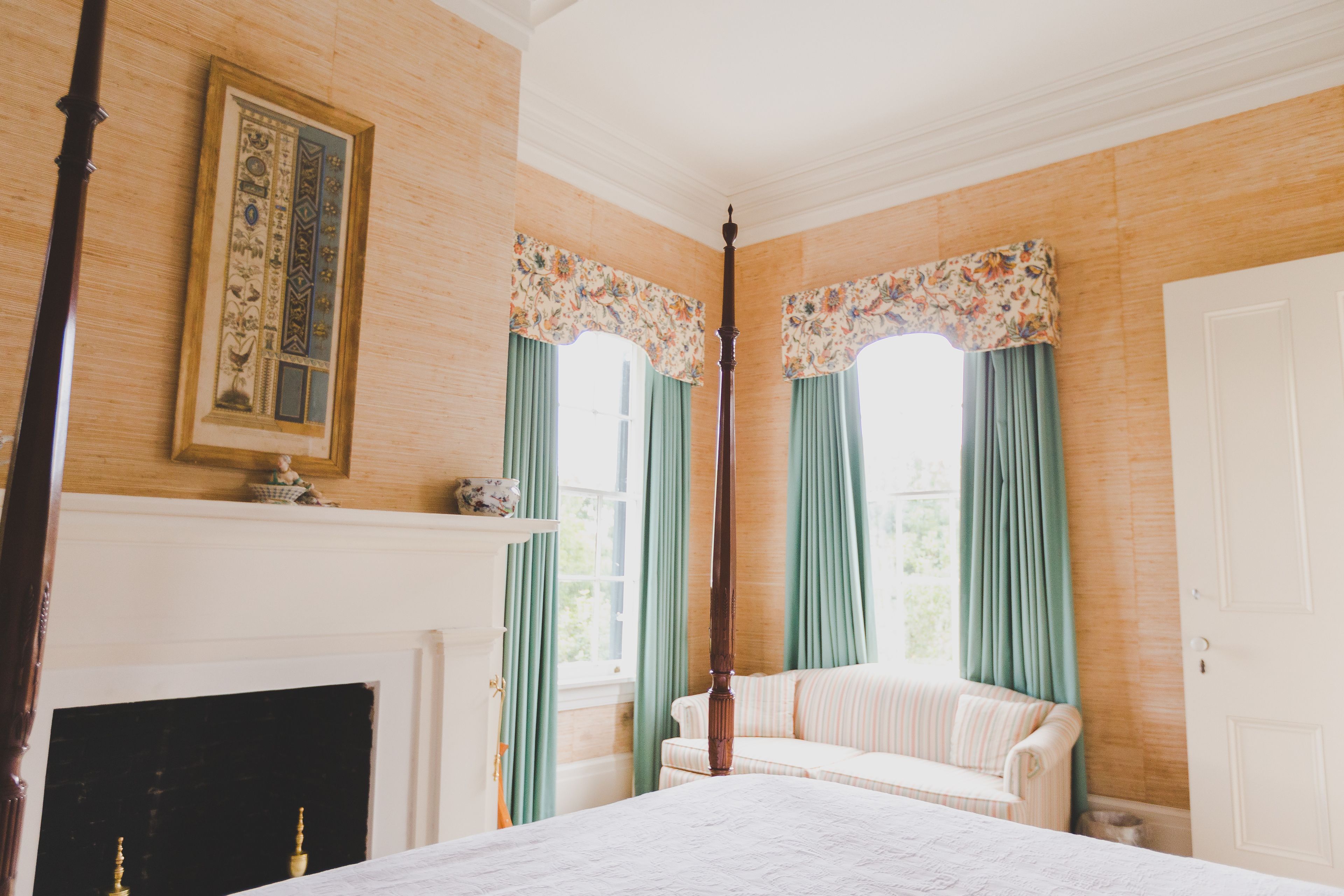 Una habitación con cama, chimenea, sofá y ventana con cortinas.