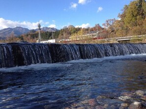 A waterfall with a clear view of the surrounding landscape, including trees and mountains in the background.