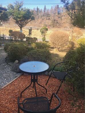 An outdoor seating area with a round table and chairs, surrounded by gravel and plants.