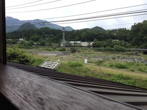 A view from a window overlooking a railway track, with a bridge and greenery in the background.