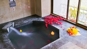 Un área de spa con un jacuzzi, una ventana con vistas y un arreglo floral en el suelo.