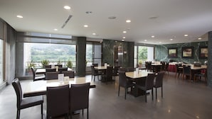 Un restaurante espacioso con paredes de mármol, ventanas amplias y vistas al exterior.
