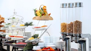 A buffet setup with various food items, including fruits, cereals, and beverages.
