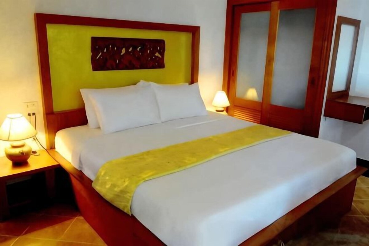A hotel room with a bed, nightstands, and a mirror.