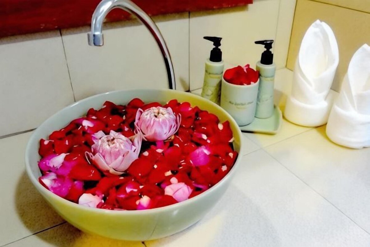 A bathroom sink with red rose petals and two onions.