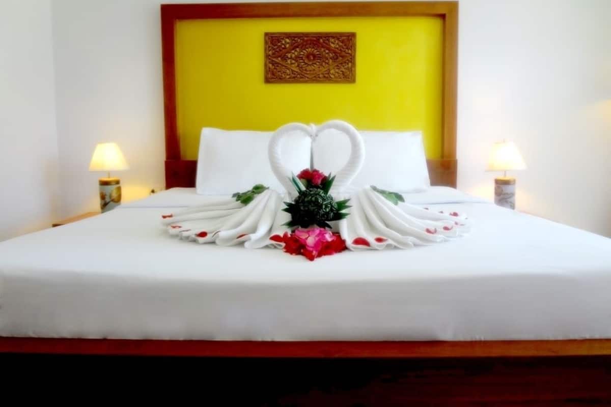 Ein ordentlich bezogenes Bett mit weißen Leinen und einer dekorativen Schwanen-Handtuch-Arrangement.