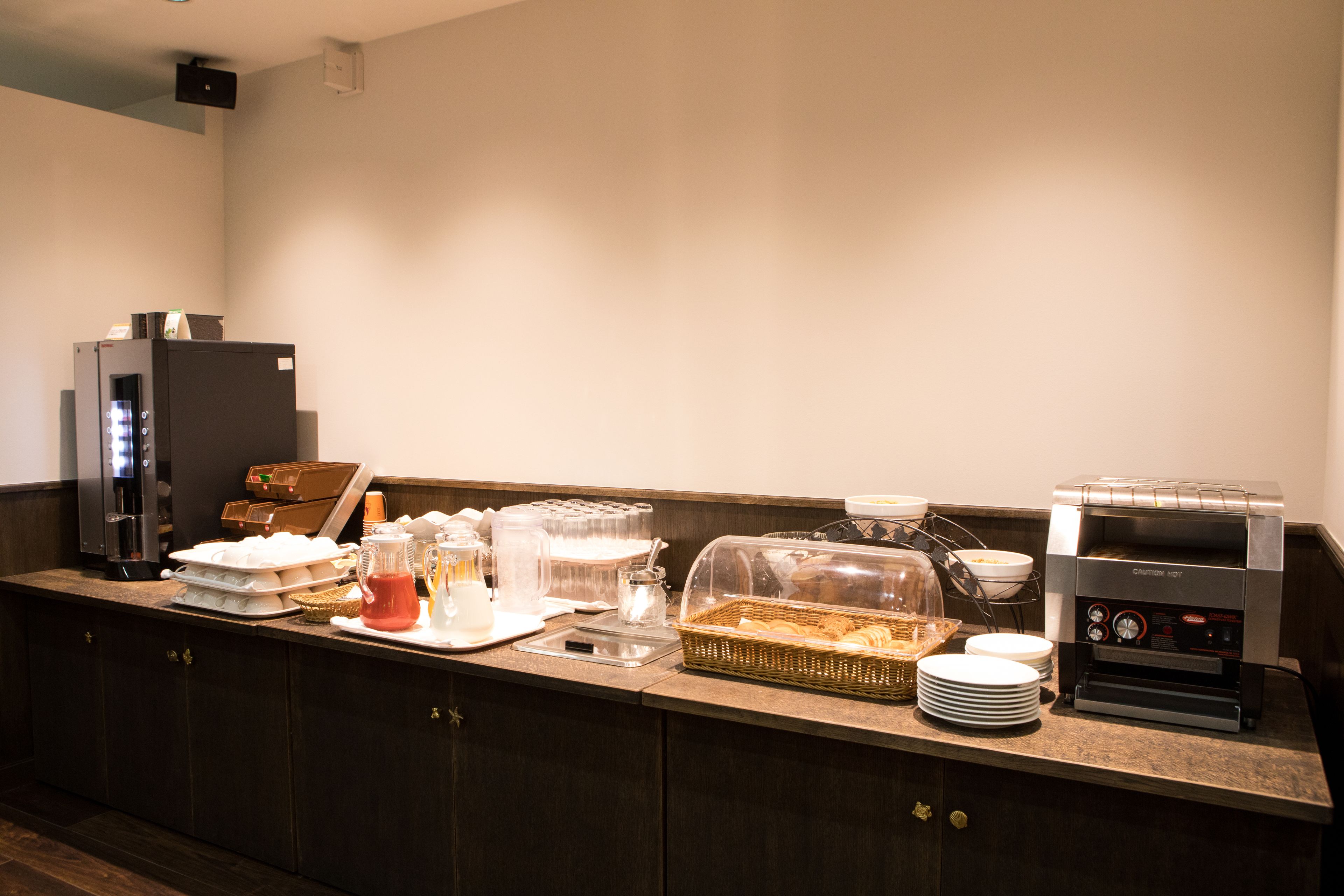 A buffet setup with a coffee machine, a refrigerator, and various food items.