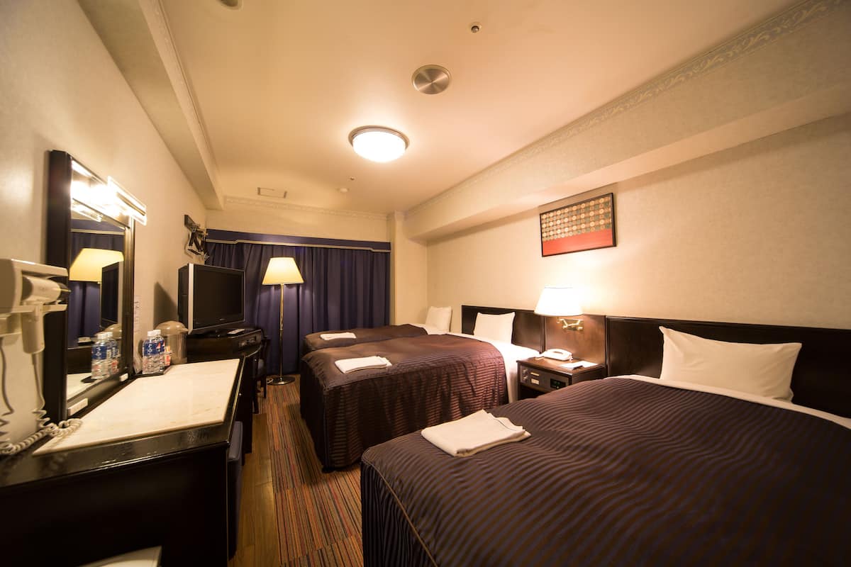 Habitación de hotel con dos camas, un escritorio y un teléfono, y un espejo.