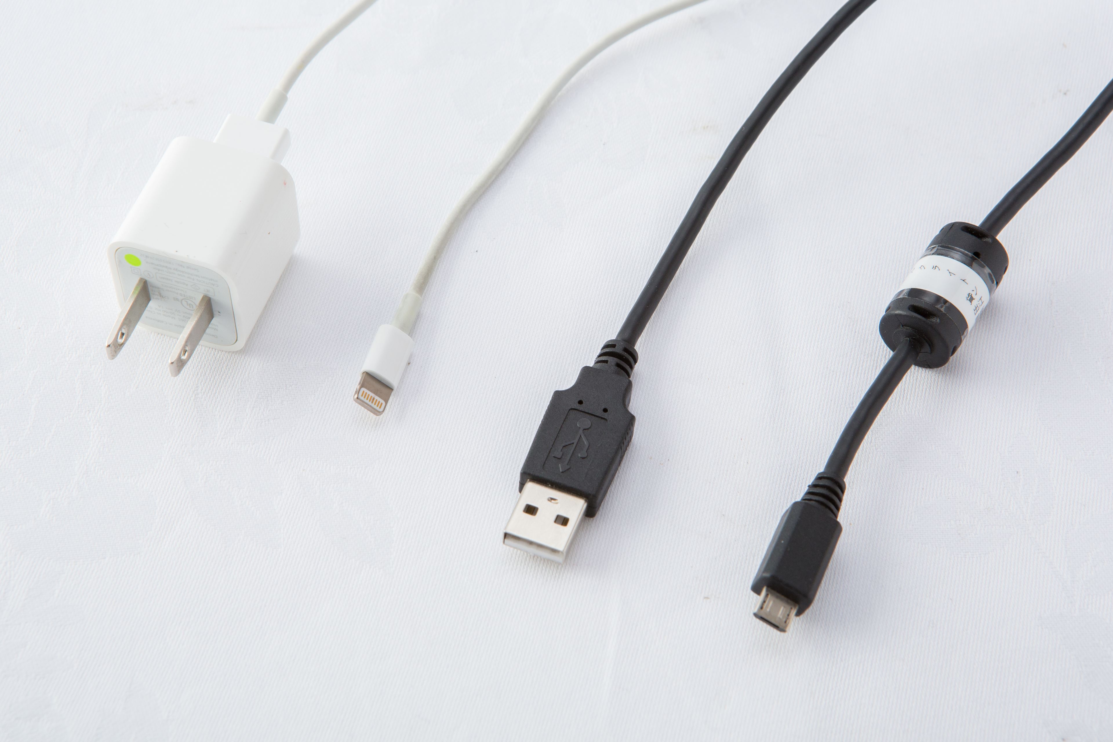 Three USB cables of different types and lengths laid out on a white surface.