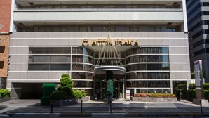 A modern hotel entrance with a curved facade, large glass windows, and a prominent entrance canopy.