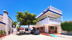 A two-story building with a balcony, a car parked in front, and a tree. - Playa Azul Kino (Bahía Kino)