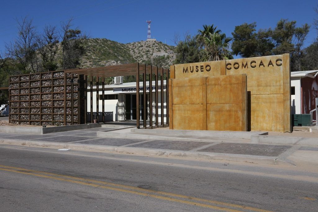 Entrada de un museo con un portón de madera y un letrero que dice "MUSEO COMCAAC".