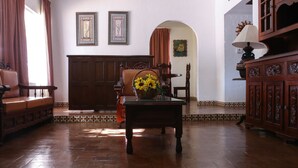 A room with a wooden floor, a sofa, a table with a vase of flowers, and a cabinet. - Playa Azul Kino (Bahía Kino)