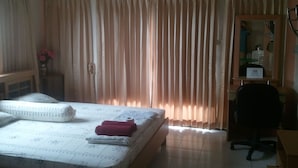A hotel room with a bed, a desk, an air conditioner, and curtains. - M&A Guesthouse (Hua Hin)