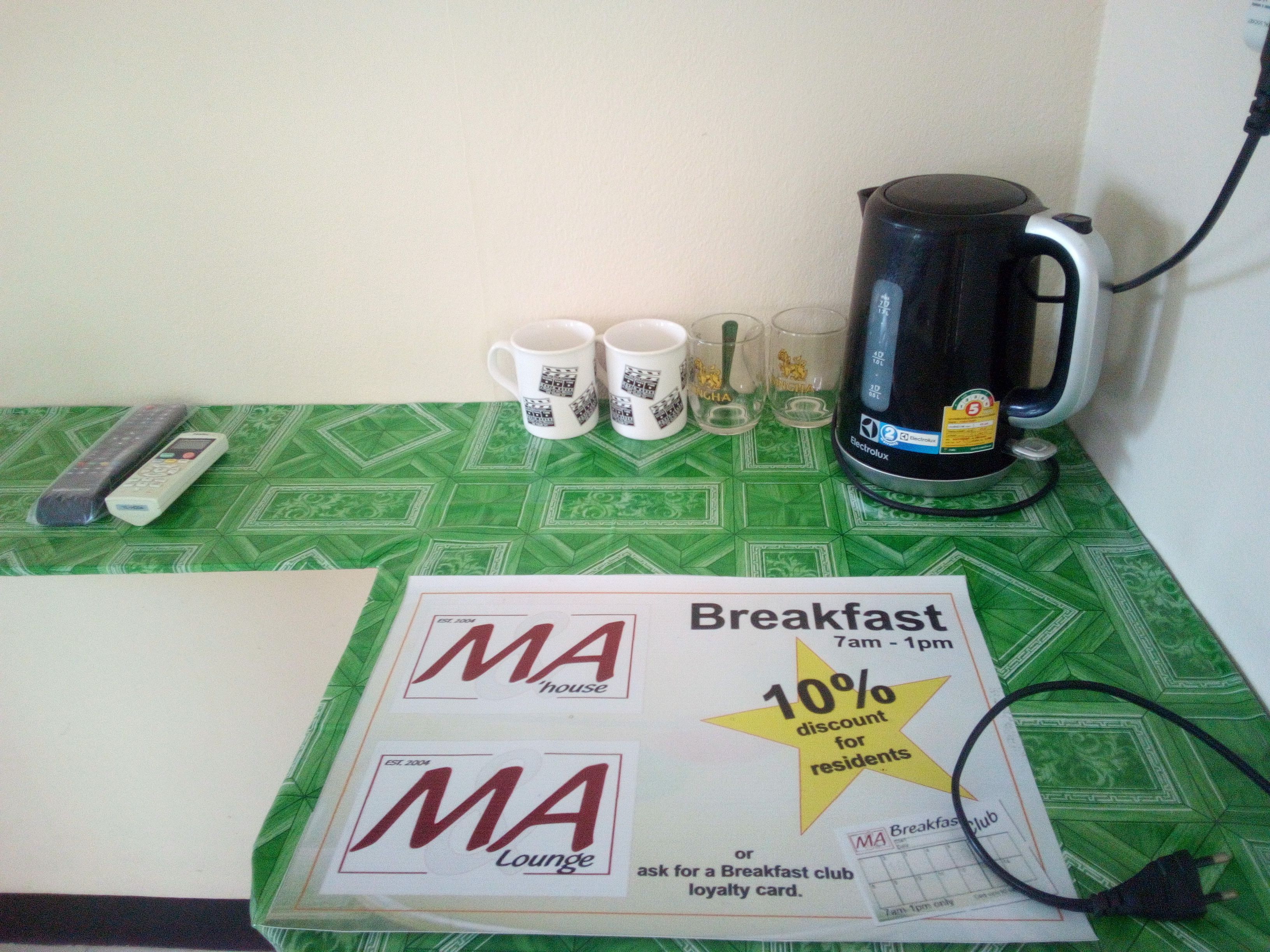 A breakfast table with a coffee maker, mugs, and a loyalty card.
