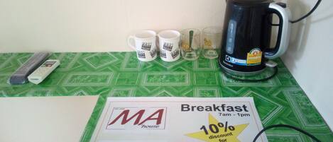 A breakfast table with a coffee maker, mugs, and a loyalty card.