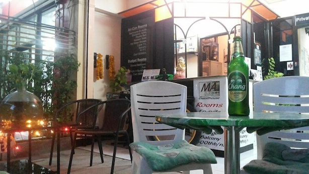 A hotel room with a balcony, a table with chairs, and a sign indicating 'MA Guesthouse Rooms'. - M&A Guesthouse (Hua Hin)