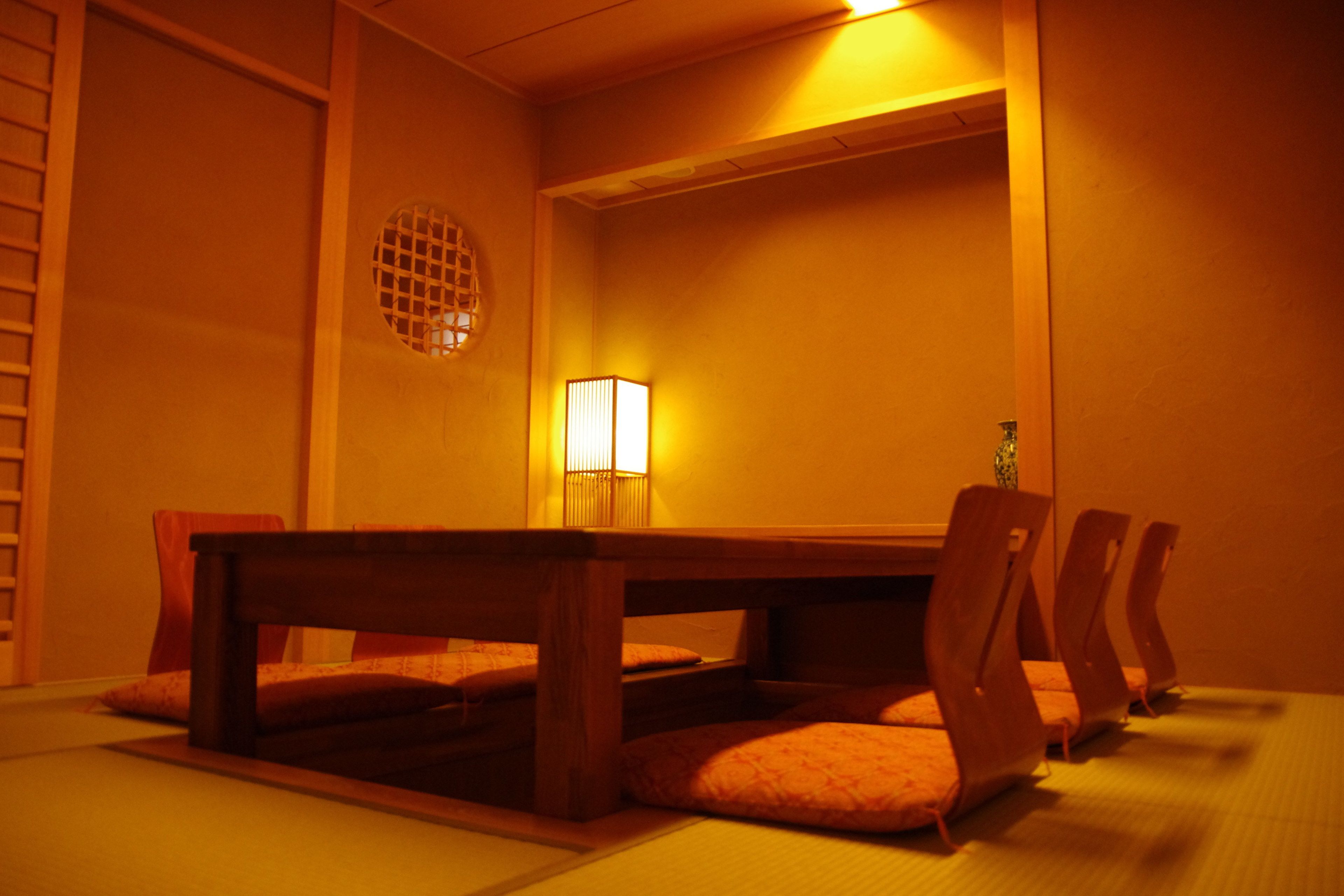 A traditional Japanese room with tatami flooring, a low wooden table, and matching chairs.