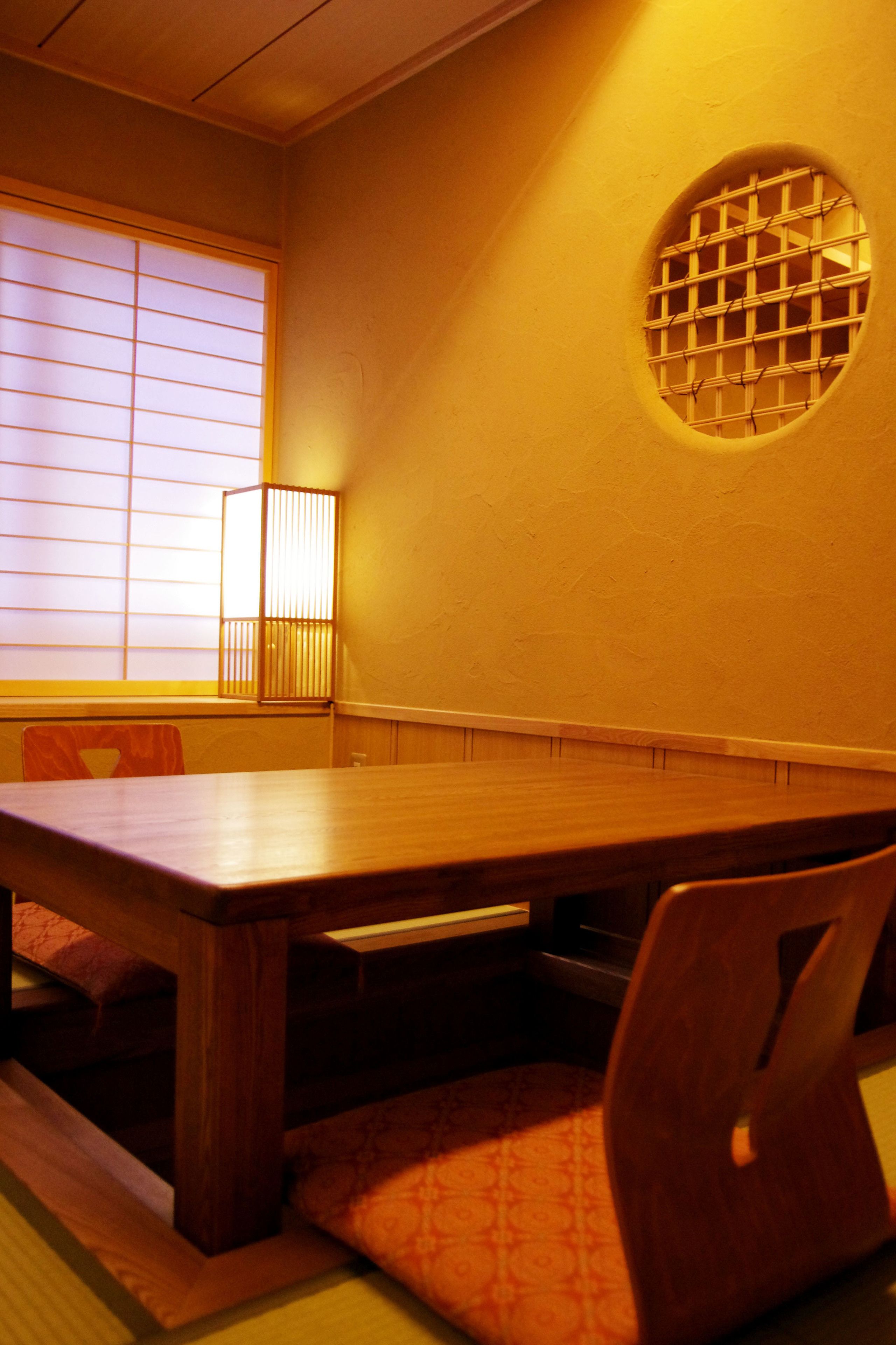 A traditional Japanese room with tatami flooring, a low wooden table, and a shoji screen window.