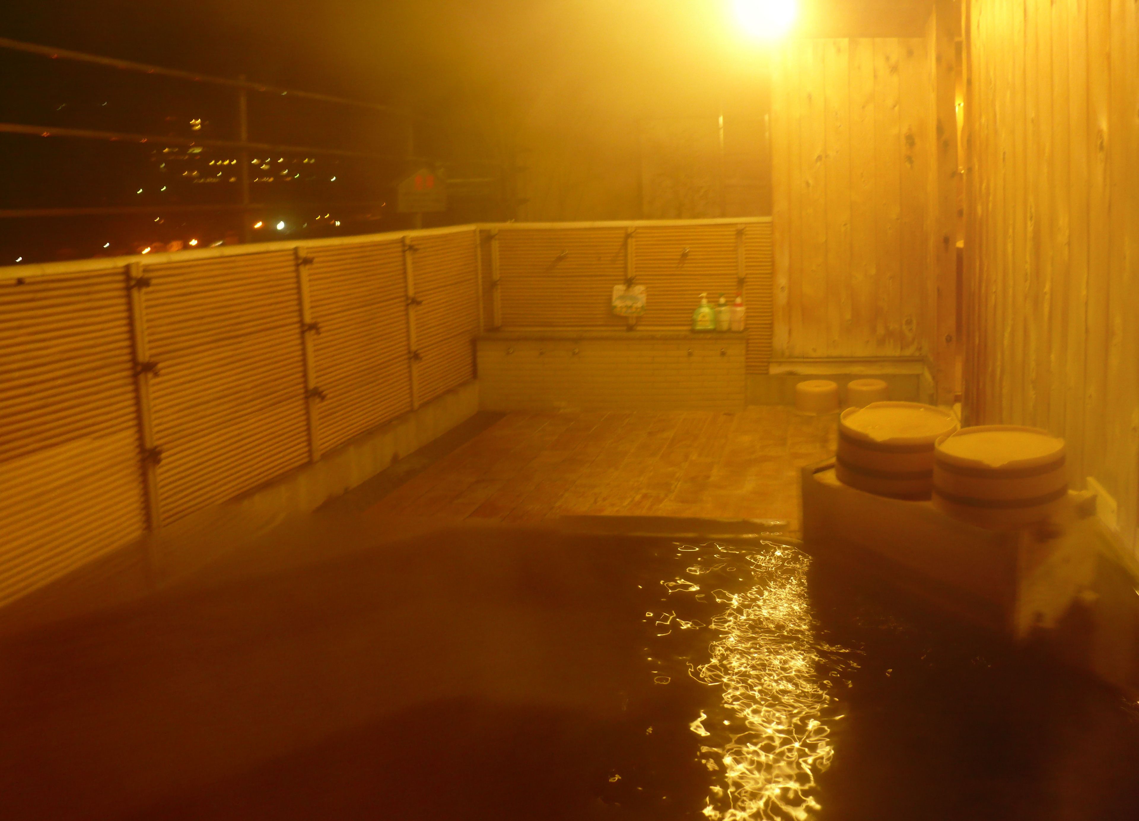 Un área de baños termales con barandales de madera y dos taburetes de madera.