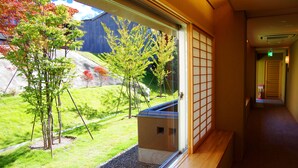 Une vue depuis une fenêtre donnant sur un jardin et un bâtiment à l’extérieur.