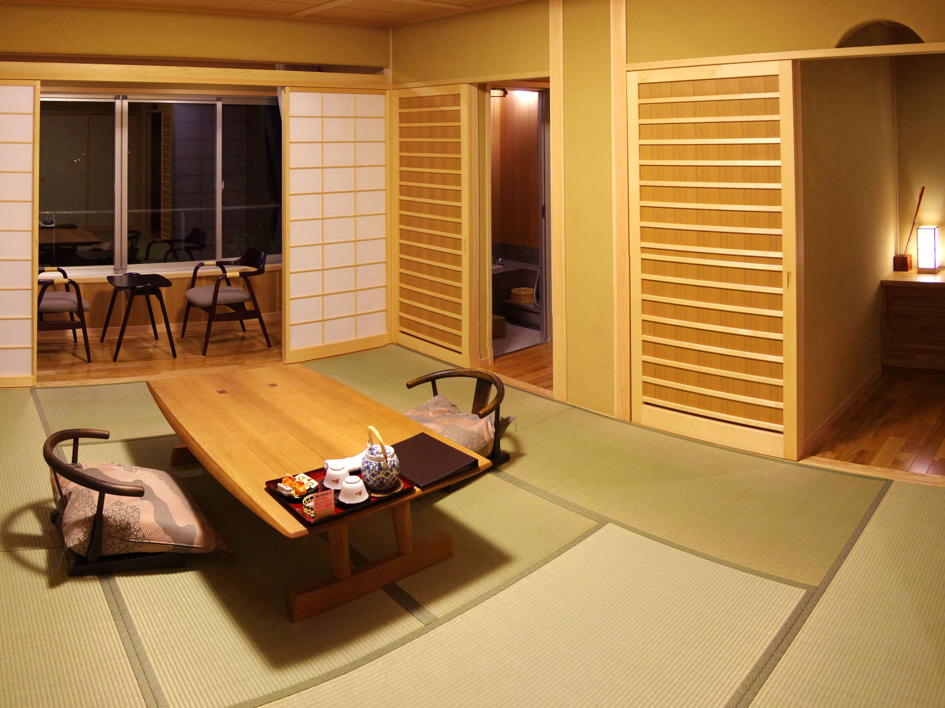 A traditional Japanese room with tatami flooring, a low wooden table with a tea set, and sliding doors.