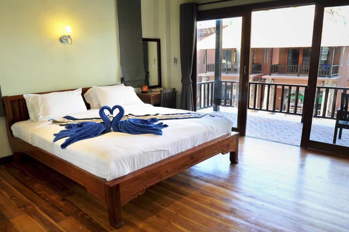 Ein hölzernes Bett mit weißen Leinentüchern und blauen Handtüchern, die in Herzform angeordnet sind.