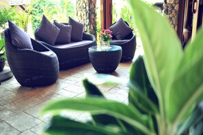 A patio area with wicker furniture and a small table with flowers. - Koh Tao Beach Club (Koh Tao)