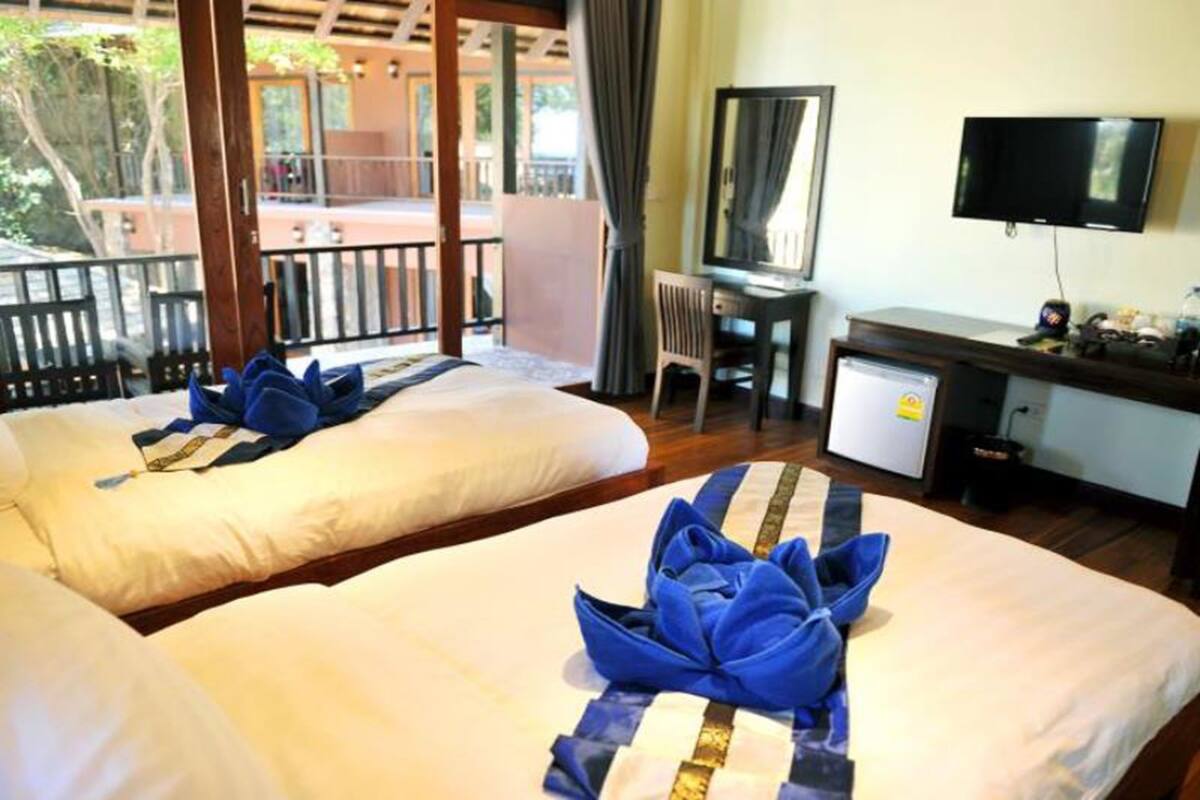 Ein Hotelzimmer mit zwei Betten, einem Schreibtisch, einem Fernseher und einem Balkon.
