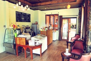 A cozy interior with a wooden table, chairs, a refrigerator, a coffee machine, and a menu board.