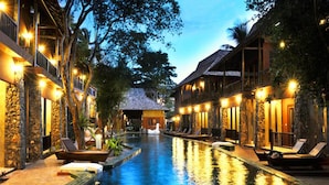 A serene hotel pool area with stone walls, lounge chairs, and a central water feature. - Koh Tao Beach Club (Koh Tao)