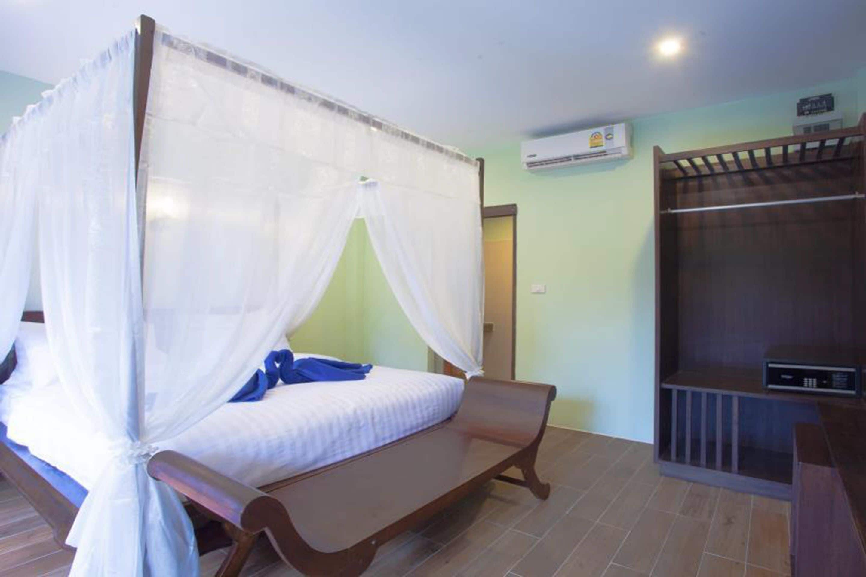 A single bed with a canopy, a wooden bench, a wardrobe, and an air conditioning unit.