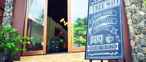 A coffee shop signboard with amenities like free wifi, home-made ice cream, and bakery.