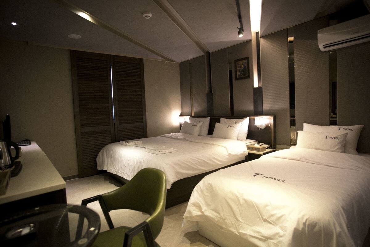 Una habitación de hotel con dos camas, un escritorio, una silla y una mesita de noche.