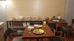 Comedor con varias mesas, cada una dispuesta con platos de comida, tazones y un vaso de leche.