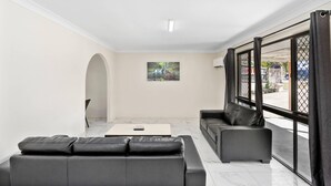 Una sala de estar moderna con un sofá, una mesa de centro y un amplio ventanal con cortinas.