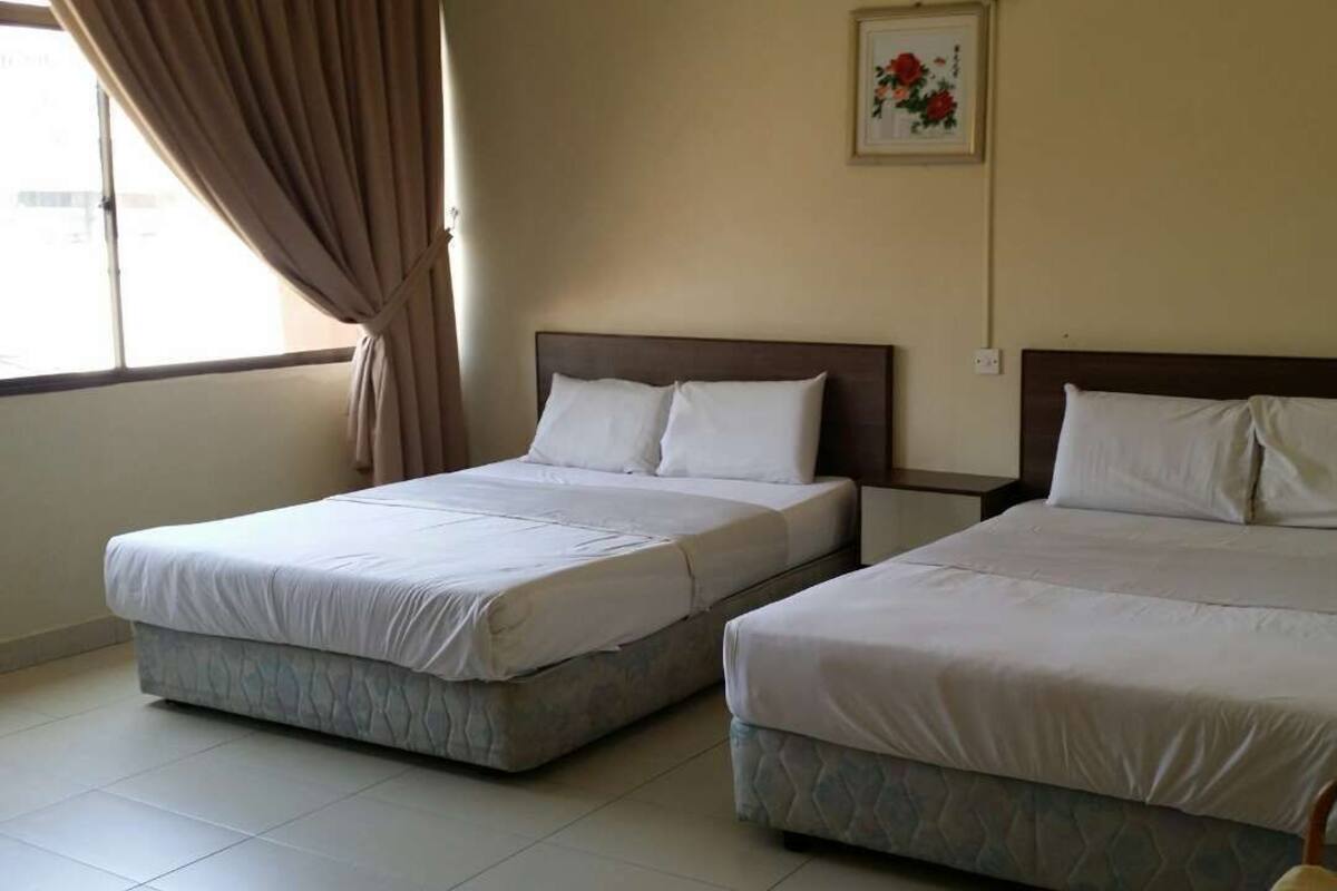 Two single beds with headboards, a window with curtains, and a framed picture on the wall.