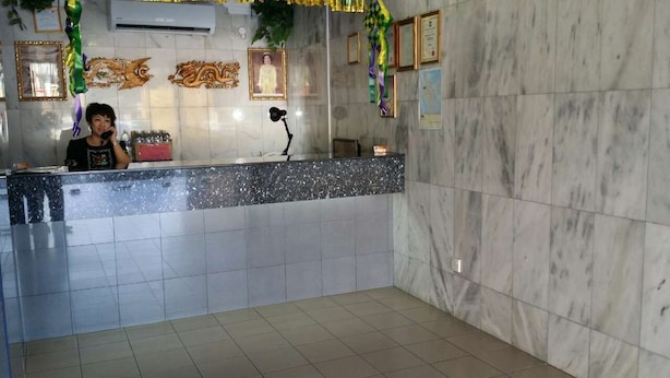A reception area with a marble counter, framed pictures on the wall, and a plant. - Dragon & Phoenix Hotel (Ipoh)
