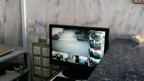 A security monitor displaying multiple camera feeds in a room with marble walls and a granite countertop. - Dragon & Phoenix Hotel (Ipoh)