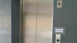 An elevator with a digital display, a sign indicating free WiFi, and a flush door. - Dragon & Phoenix Hotel (Ipoh)