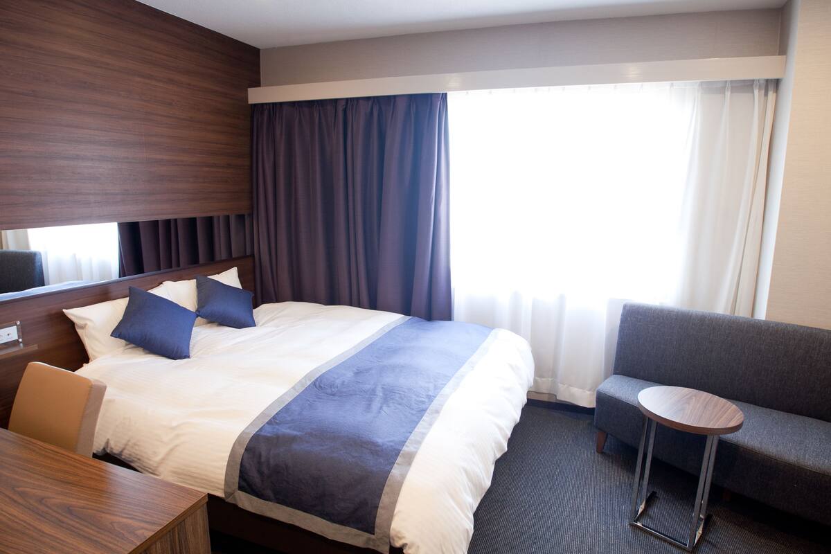 Une chambre d’hôtel avec un grand lit, un canapé, une petite table ronde et un bureau.